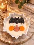 Handgegossene Halloween-Dekokerze in weißer Zierschale mit Fledermaus, Kürbissen und Herbstmotiv | Flomati